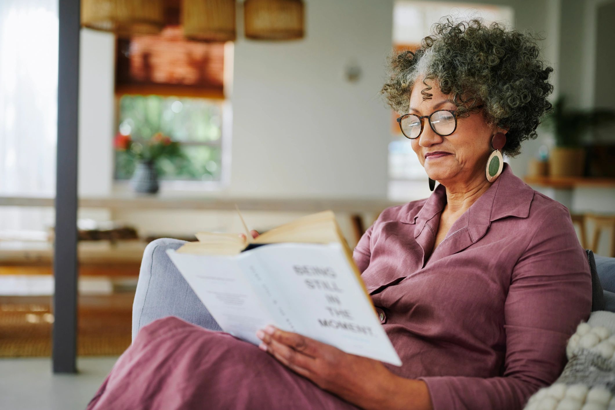 Mature woman relaxing with a book on her living room sofa